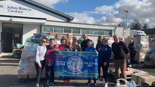 Picture from the Harps collection for Ukraine earlier this year showing various people including Harps volunteers holding a Harps flag and many boxes collected