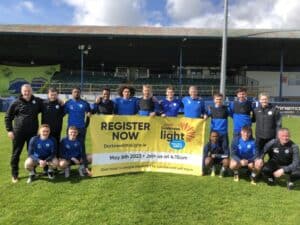 The Harps Squad Holding a Darkness into Light banner at Finn Park